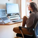 Frau im Lehrer-Arbeitszimmer, die am Laptop arbeitet und telefoniert.
