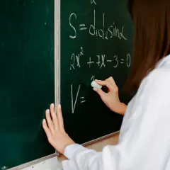 Eine Hand schreibt mit Kreide Formeln an eine Tafel. So kann man Mathe besser verstehen und komplexe Gleichungen lösen.