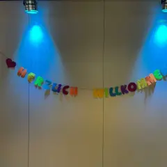 Bunte Buchstaben-Girlande "HERZLICH WILLKOMMEN" mit Herzen, beleuchtet von blauen Spots. Tolle Ideen für einen Kennenlernnachmittag in der Grundschule!