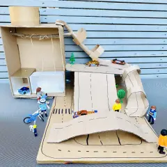 Kreatives Basteln mit Karton: Eine Spielzeugwelt mit Autos, Figuren und Rampen entsteht.