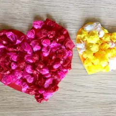 Zwei bunte Herzen, rot und gelb, mit zerknülltem Seidenpapier beklebt. Perfekt zum Herzen basteln mit Kindern!