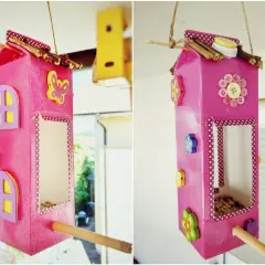 Selbstgebaute Vogelfutterstation aus Milchkarton, dekoriert mit Knöpfen und Holzblumen. Ein tolles Projekt zum vogelfutterstation selber bauen mit kindern.