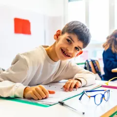 Ein lächelnder Junge lernt in einem Klassenzimmer. Dies ist ein Beispiel für **Inklusion an Schulen**, wo alle Kinder gemeinsam lernen und wachsen.