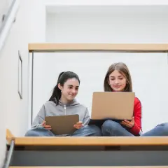 Zwei Mädchen lernen auf Laptops und Tablets. Die Digitalisierung an Schulen Statistik zeigt, wie wichtig diese Geräte für die Bildung sind.
