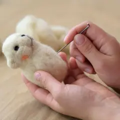Hände formen mit Nadel und Wolle ein süßes Tierchen. Perfekt für trockenfilzen mit Kindern.