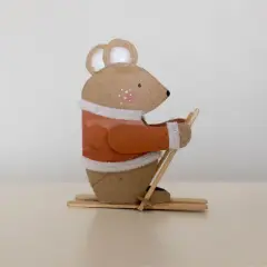 Süße Maus beim Skifahren, ein tolles Beispiel für Basteln mit Papprollen. Sie trägt einen orangen Pullover und hält Skistöcke.