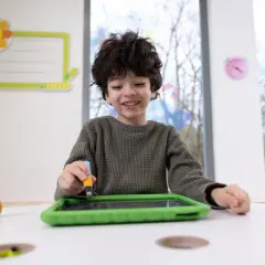 Ein Junge übt mit einem Stift auf einem Tablet, was eine spielerische Art ist, graphomotorische Fähigkeiten zu entwickeln.