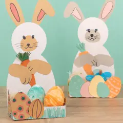 Zwei süße Osterhasen zum osterhase basteln halten Karotten. Bunte Ostereier liegen in Körbchen.