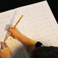 Kind löst einen dyskalkulie test mit Symbolen. Ein Bleistift zeigt auf ein Symbol auf dem Blatt.