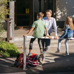 Ein Mann spricht mit zwei Kindern vor einer Schule. Vielleicht plant er, als lehrer bundesland wechseln.