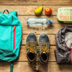 Rucksack, Schuhe, Jacke, Wasserflasche, Obst und Lunchbox – alles für die Klassenfahrt Packliste bereit.