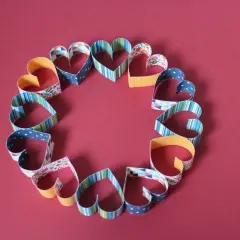 Ein Kreis aus bunten Papierherzen, die zum **Herz basteln** einladen.