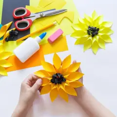 Kinder basteln bunte Papierblumen. Schere, Kleber und Papier liegen bereit für kreative Projekte.