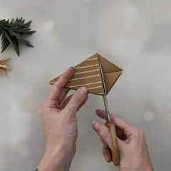 Schere schneidet Papier für einen Tannenbaum. Einfache Anleitung zum Falten von Tannenbäumen.