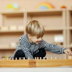 Ein Junge spielt konzentriert mit Holzbausteinen in einem Montessori Kindergarten.