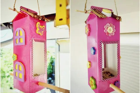 Selbstgebaute Vogelfutterstation aus Milchkarton, dekoriert mit Knöpfen und Holzblumen. Ein tolles Projekt zum vogelfutterstation selber bauen mit kindern.
