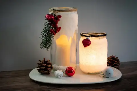 Zwei selbstgebastelte Windlichter mit Salz, Kerzen und weihnachtlichem Schmuck. Ein DIY-Projekt, das Gemütlichkeit bringt.