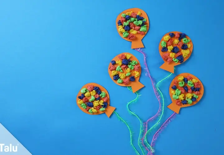 Bunte Ballons aus Papier, ideal zum Fasching Deko basteln. Kleine, zerknüllte Papierstücke in Rot, Blau, Grün und Gelb zieren die orangefarbenen Ballons.