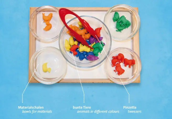 Bunte Tierfiguren in Schalen, bereit für spannende Aktionstabletts im Kindergarten. Mit Pinzetten sortieren und lernen.