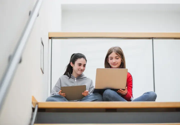 Zwei Mädchen lernen auf Laptops und Tablets. Die Digitalisierung an Schulen Statistik zeigt, wie wichtig diese Geräte für die Bildung sind.