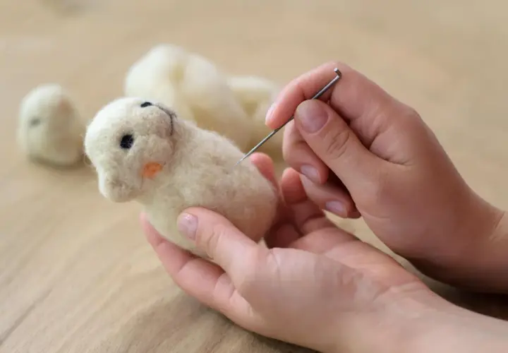Hände formen mit Nadel und Wolle ein süßes Tierchen. Perfekt für trockenfilzen mit Kindern.