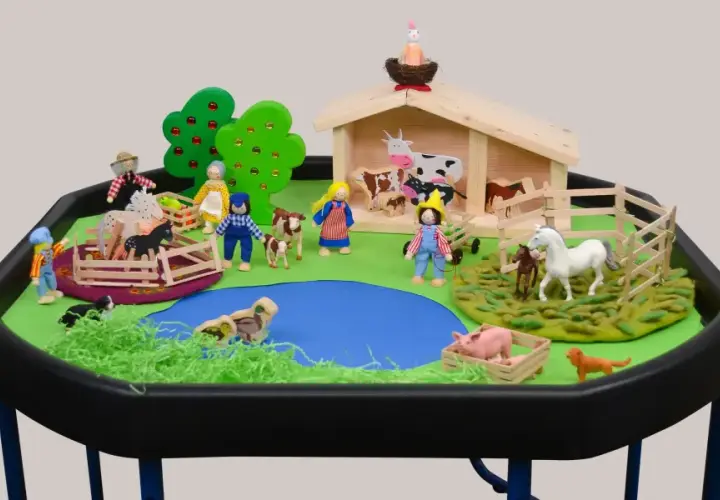 Spielerische Szene für den Morgenkreis Thema Bauernhof: Kinderfiguren, Tiere und ein Stall laden zum Entdecken ein.