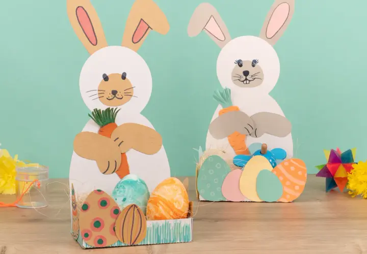 Zwei süße Osterhasen zum osterhase basteln halten Karotten. Bunte Ostereier liegen in Körbchen.