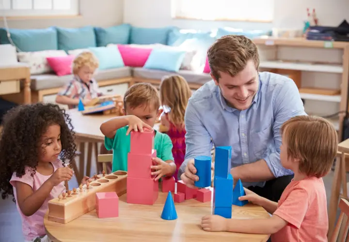 Lehrer fördert mathematische Bildung in der Kita durch spielerisches Bauen mit geometrischen Formen.