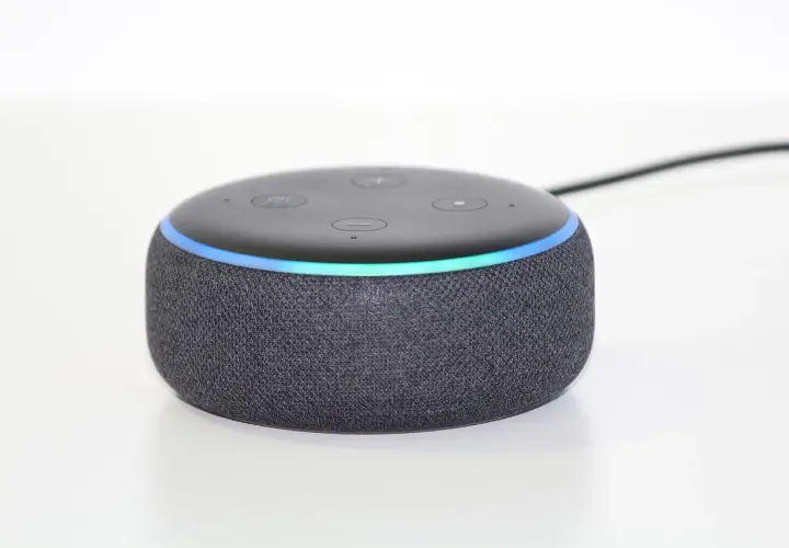 Ein grauer Echo Dot mit leuchtendem Ring, bereit, Alexa Skills zu aktivieren und dein Zuhause zu steuern.