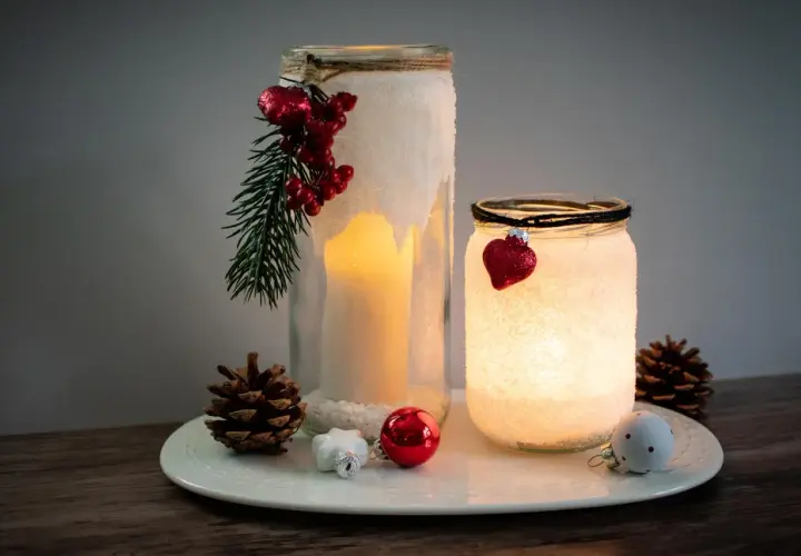 Zwei selbstgebastelte Windlichter mit Salz, Kerzen und weihnachtlichem Schmuck. Ein DIY-Projekt, das Gemütlichkeit bringt.