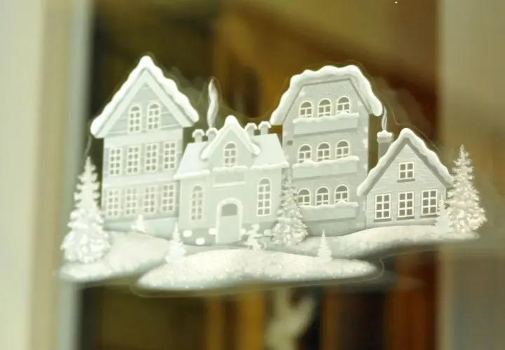 Winterliche Häuser mit Schnee bedeckt, ein Beispiel für schöne Fensterbilder basteln.