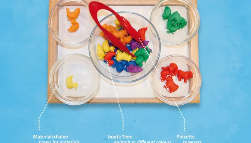 Bunte Tierfiguren in Schalen, bereit für spannende Aktionstabletts im Kindergarten. Mit Pinzetten sortieren und lernen.