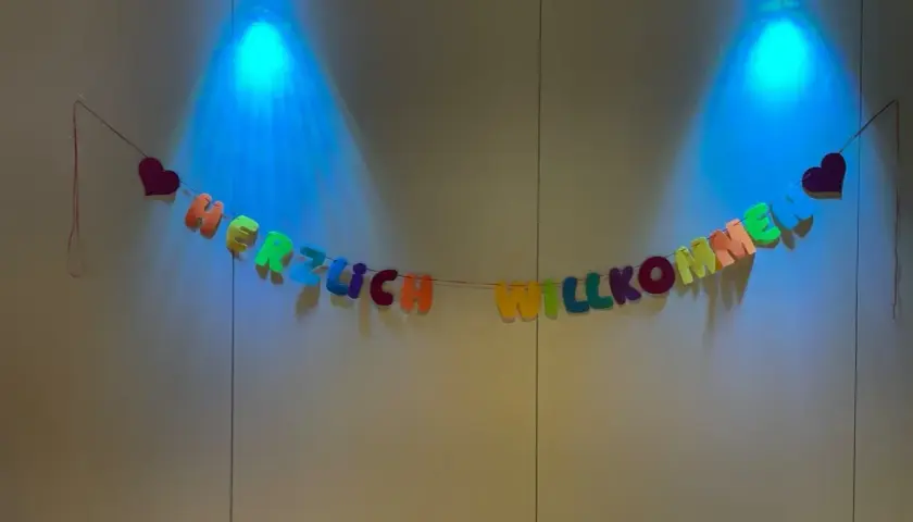 Bunte Buchstaben-Girlande "HERZLICH WILLKOMMEN" mit Herzen, beleuchtet von blauen Spots. Tolle Ideen für einen Kennenlernnachmittag in der Grundschule!