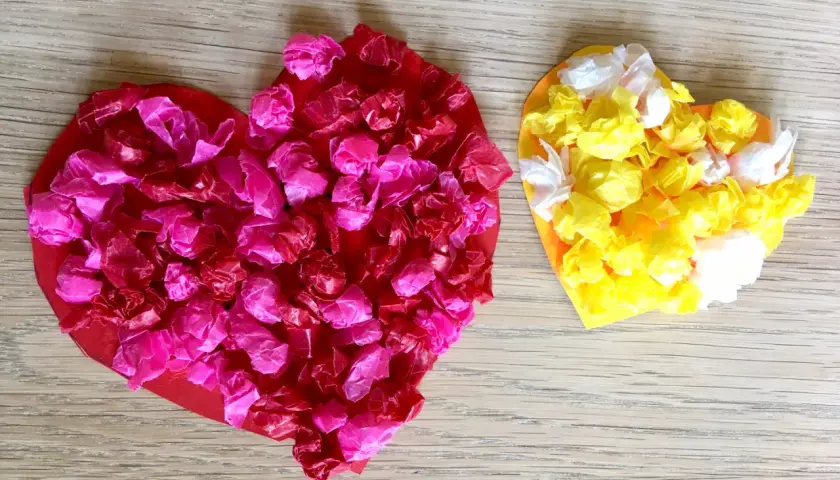 Zwei bunte Herzen, rot und gelb, mit zerknülltem Seidenpapier beklebt. Perfekt zum Herzen basteln mit Kindern!