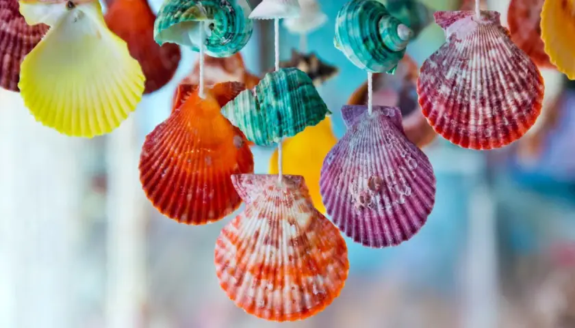 Bunte, bemalte Muscheln hängen an Schnüren und bilden eine fröhliche Dekoration.