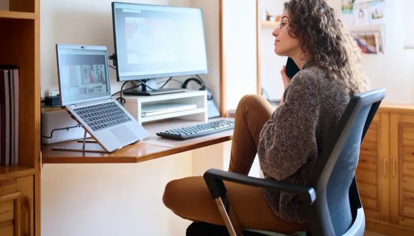 Frau im Lehrer-Arbeitszimmer, die am Laptop arbeitet und telefoniert.