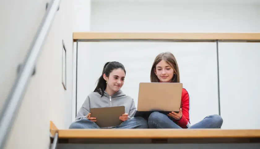 Zwei Mädchen lernen auf Laptops und Tablets. Die Digitalisierung an Schulen Statistik zeigt, wie wichtig diese Geräte für die Bildung sind.