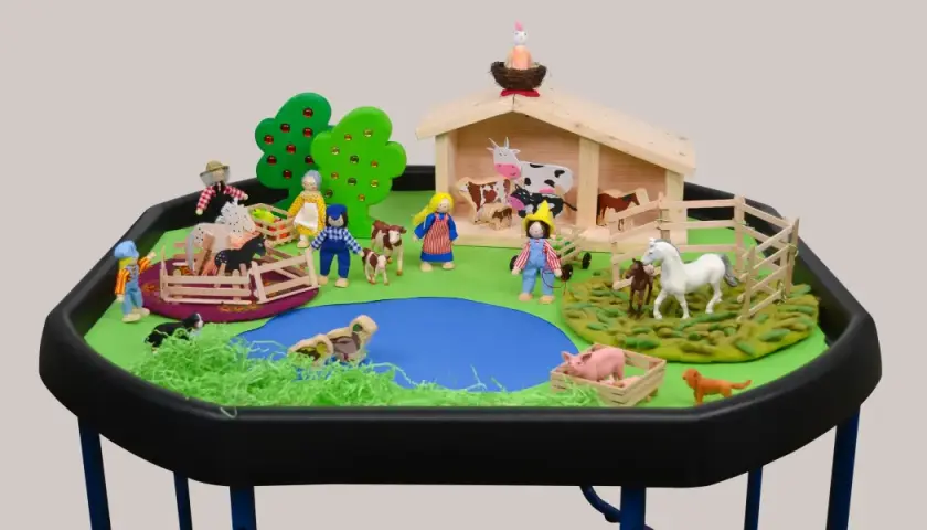 Spielerische Szene für den Morgenkreis Thema Bauernhof: Kinderfiguren, Tiere und ein Stall laden zum Entdecken ein.