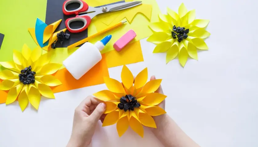 Kinder basteln bunte Papierblumen. Schere, Kleber und Papier liegen bereit für kreative Projekte.