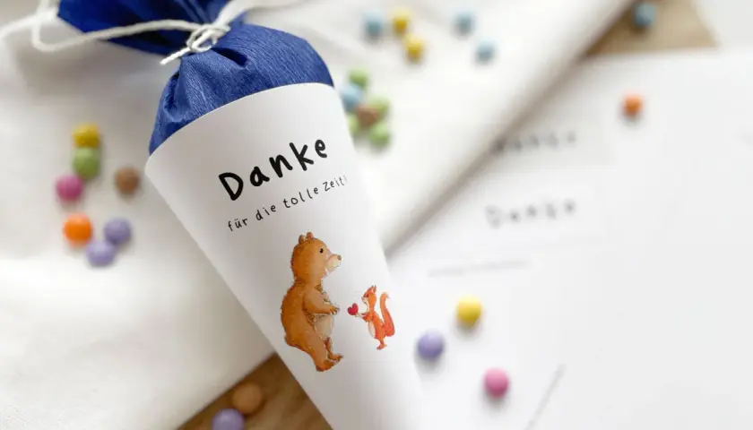 Ein liebevoll gestalteter Zuckertüte für das Kindergarten-Basteln: Ein Bär und ein Eichhörnchen mit Herz, umgeben von bunten Schokolinsen.