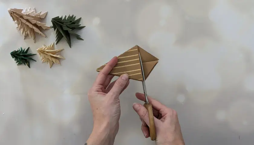 Schere schneidet Papier für einen Tannenbaum. Einfache Anleitung zum Falten von Tannenbäumen.