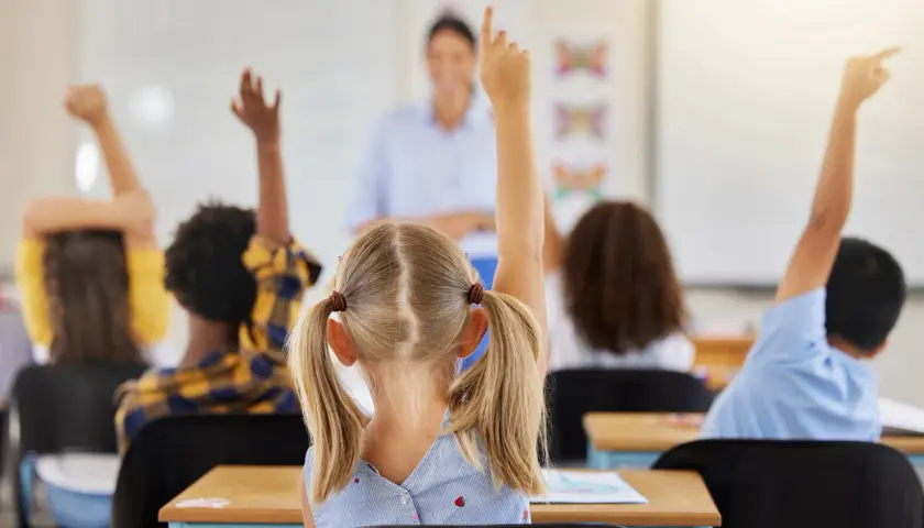 Kinder melden sich im Unterricht, um Fragen zu beantworten. Ein guter Start in der neuen Schule!