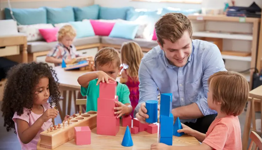 Lehrer fördert mathematische Bildung in der Kita durch spielerisches Bauen mit geometrischen Formen.
