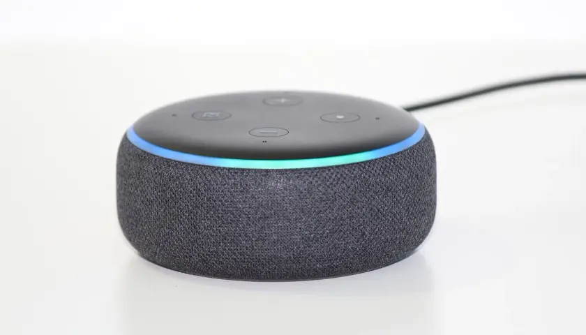 Ein grauer Echo Dot mit leuchtendem Ring, bereit, Alexa Skills zu aktivieren und dein Zuhause zu steuern.