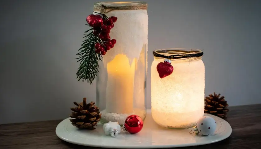 Zwei selbstgebastelte Windlichter mit Salz, Kerzen und weihnachtlichem Schmuck. Ein DIY-Projekt, das Gemütlichkeit bringt.
