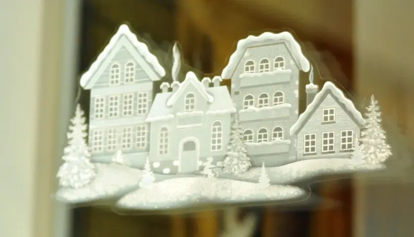 Winterliche Häuser mit Schnee bedeckt, ein Beispiel für schöne Fensterbilder basteln.