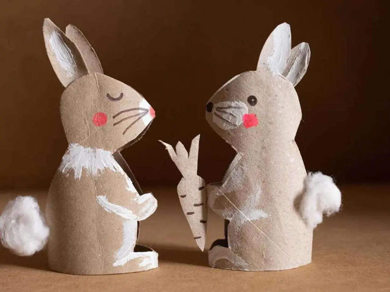 Zwei selbstgebastelte Osterhasen aus Pappe, einer mit Karotte, perfekt für osterhase basteln kinder.