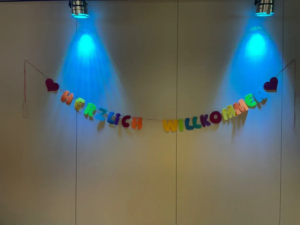 Bunte Buchstaben-Girlande "HERZLICH WILLKOMMEN" mit Herzen, beleuchtet von blauen Spots. Tolle Ideen für einen Kennenlernnachmittag in der Grundschule!