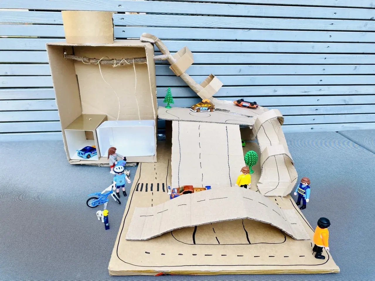 Kreatives Basteln mit Karton: Eine Spielzeugwelt mit Autos, Figuren und Rampen entsteht.