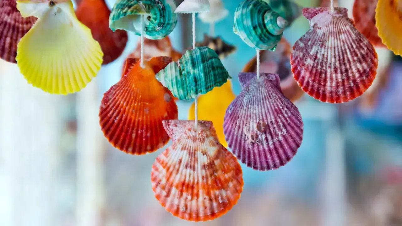 Bunte, bemalte Muscheln hängen an Schnüren und bilden eine fröhliche Dekoration.